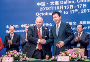 Two people shaking hands at a conference depicting businesses from Northampton and China merging