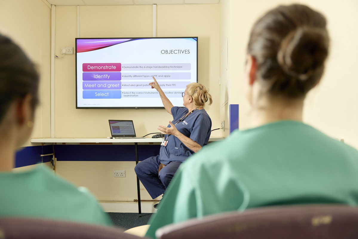 Seminar with Dental Nursing giving a presentation to a group of students at the University of Northampton. On the screen are four objectives: Demonstrate, Identify, Meet and greet, and select.
