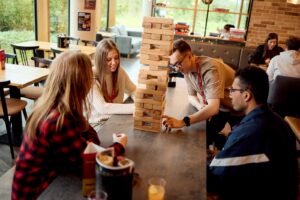 Four students playing a game of Jenga in the Waterside restaurant
