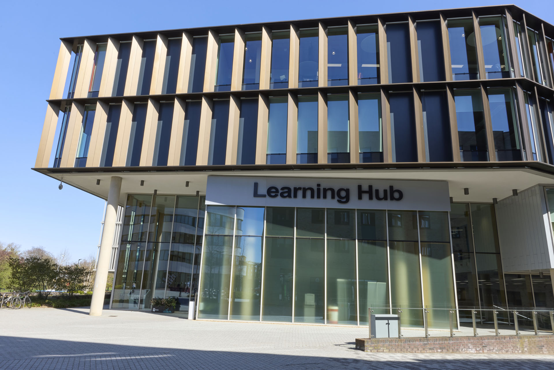 External view of the Learning Hub at the University of Northampton. The building features large glass windows, metal panelling, and pavements.