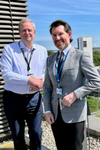 Andrew and Ben from Newslands Development, standing on the balcony at Waterside Campus shaking hands.