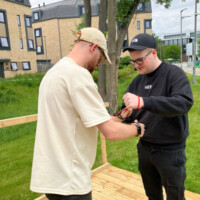 Two Education students standing outside, tying knots around their wrists in a problem solving activity.