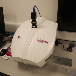 Epredia Pannoramic MIDI ll slide scanner sits on a desk in a laboratory, with cables and a computer monitor nearby.